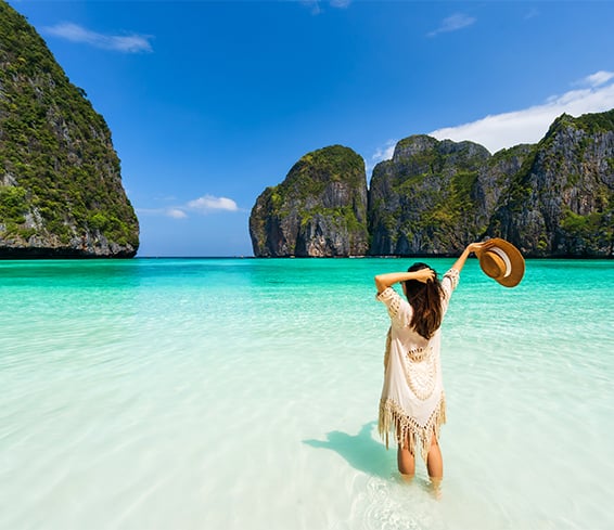 Young woman traveler relaxing and enjoying at beautiful tropical white sand beach at Maya bay in Krabi, Thailand, for a summer vacation.